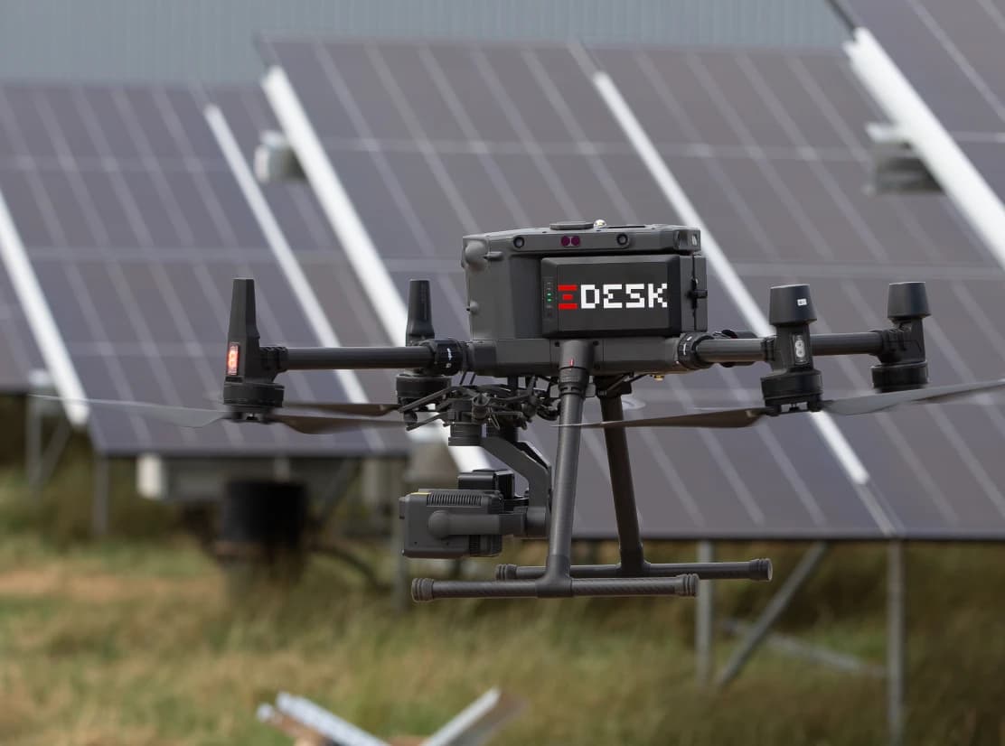 Professionelle Drohne mit Thermalkamera vor Solarpanelen.