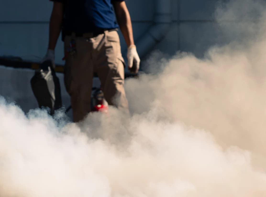 Person mit Feuerlöscher in rauchiger Umgebung.