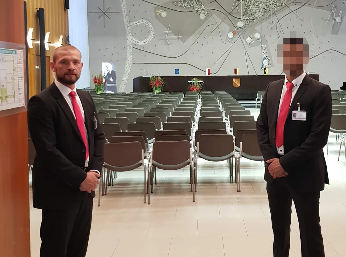 Elegante Sicherheitsprofis in Gerichtsraum-ähnlichem Event. Professionalität, Vertrauen, geordnete Sicherheit. Effektiver Eventschutz.