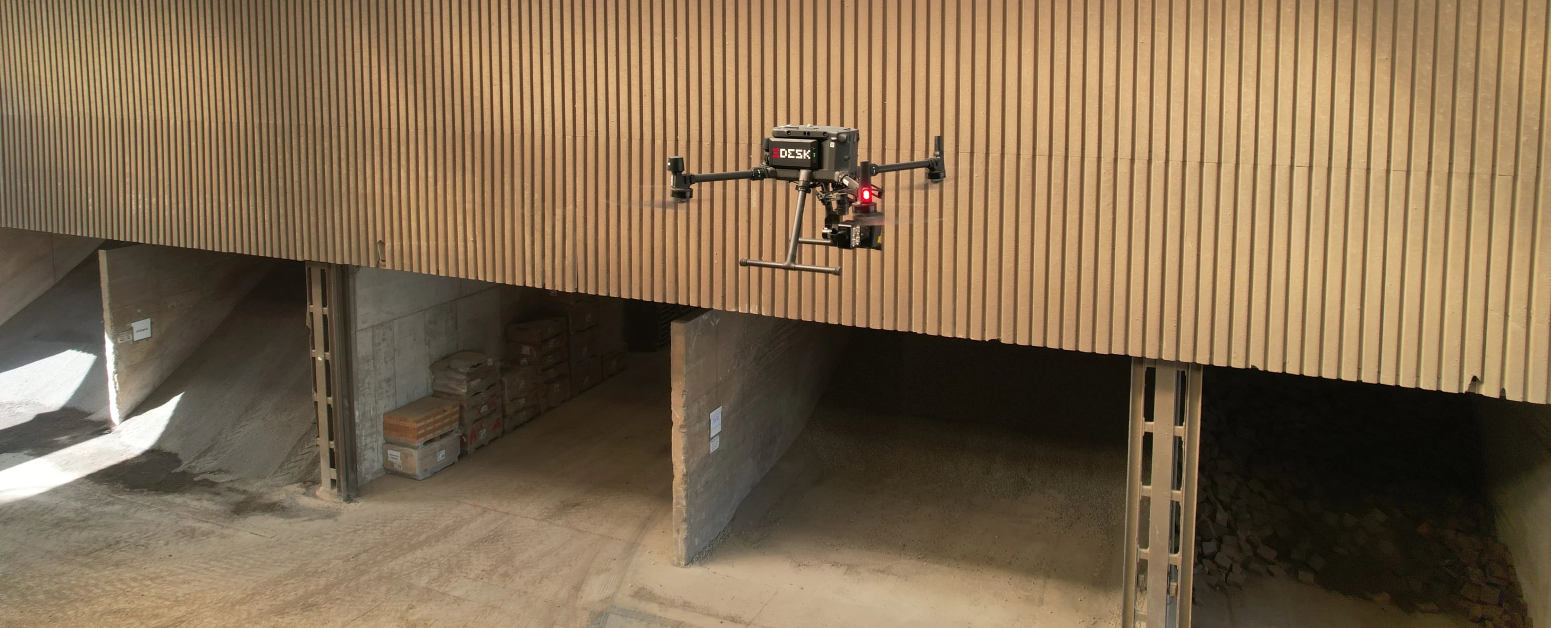 Drohnen-UAV Baustelleninspektion: Inspektionsdrohne fliegt in einer Industriehalle über Lagerflächen