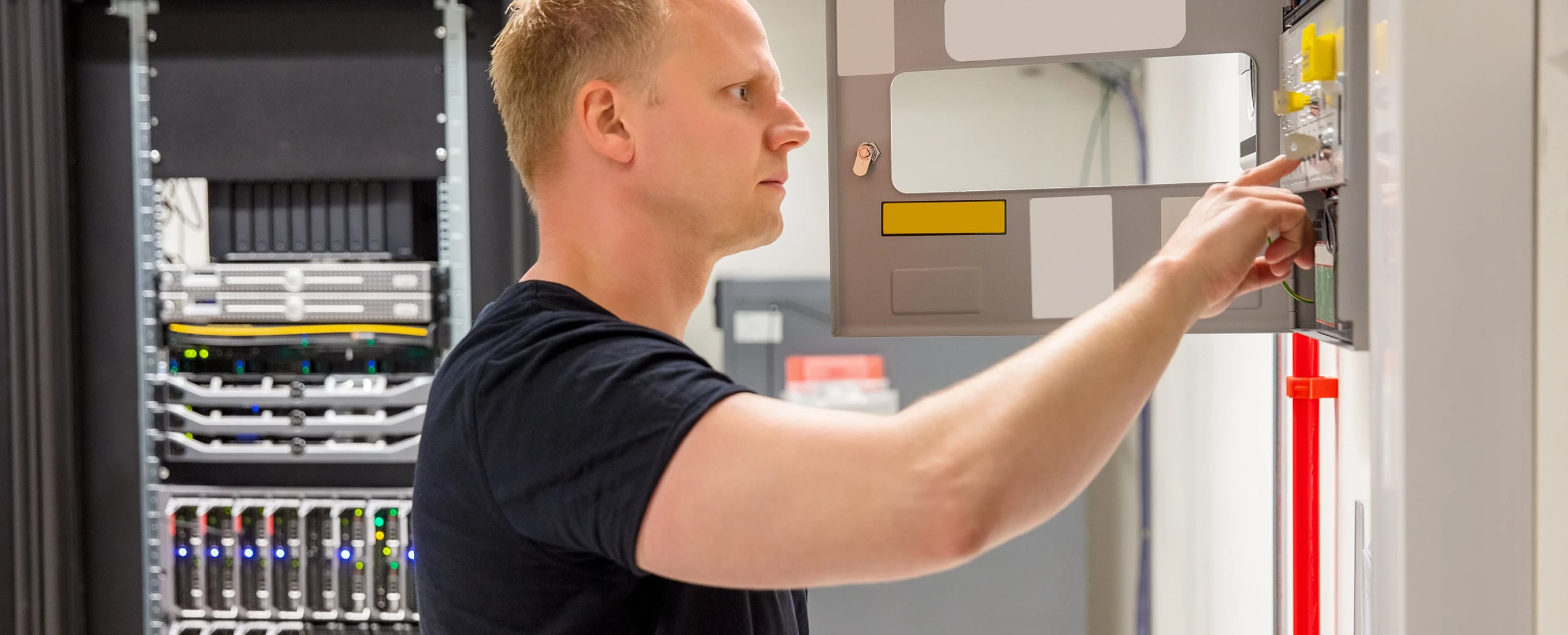 Sicherheitstechnik Brandmeldeanlagen: Techniker prüft ein Brandmeldesystem neben Serverschränken