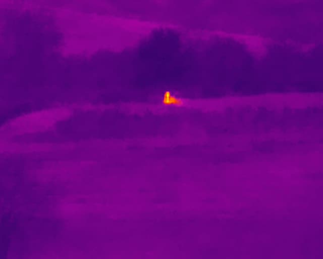 Drohnen-Thermalbild zeigt einzelnen Wärme-Hotspot in einem Holzlager bei Nacht – radiometrische Brandfrüherkennung für Sägewerke und Holzverarbeitung