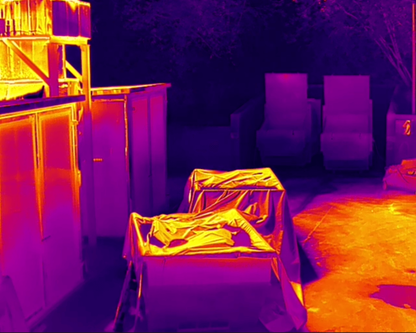 Thermalbild einer Sägewerk-Außenfläche mit abgedeckten Holzstapeln und Lagerflächen – Perimeter-Wärmebildüberwachung für Rundholz- und Schnittholzlager