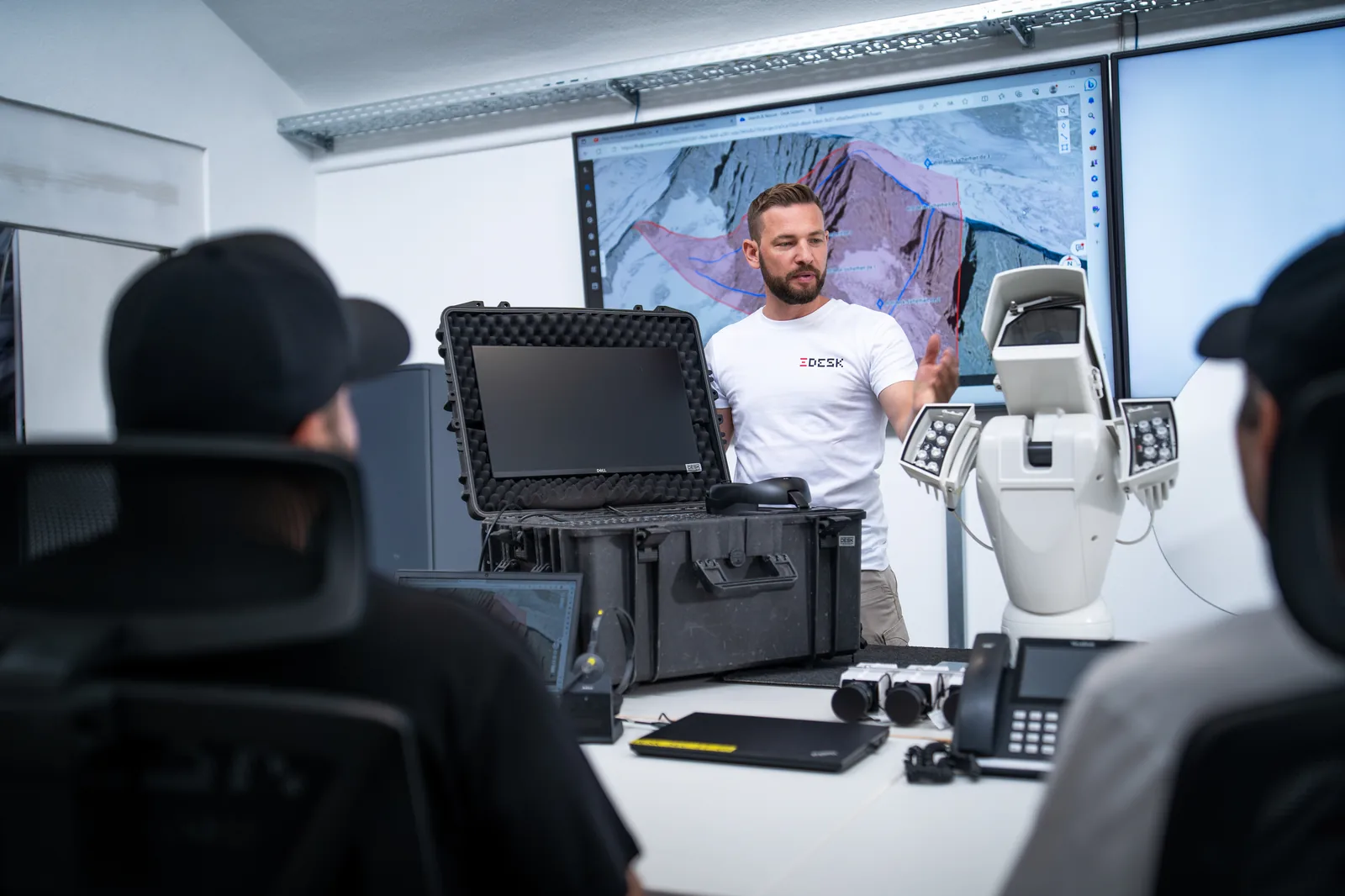 Einsatzbriefing im Control Room Karlsruhe: DESK-Sicherheit-Experte erläutert mobile Sicherheitstechnik, PTZ-Kamera und Lagebild-Analyse auf dem Großbildschirm.