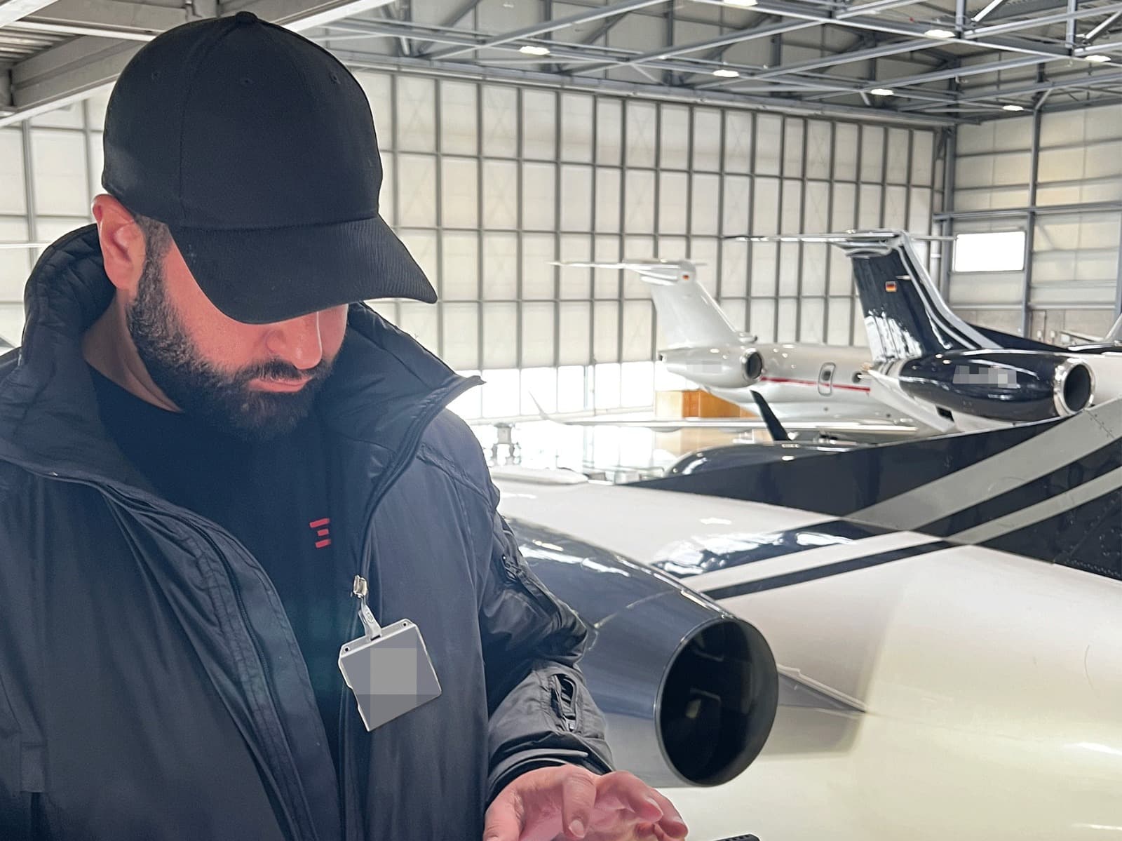DESK Sicherheit Einsatzkraft prüft mobile Detektionstechnik im Hangar neben Privatjet